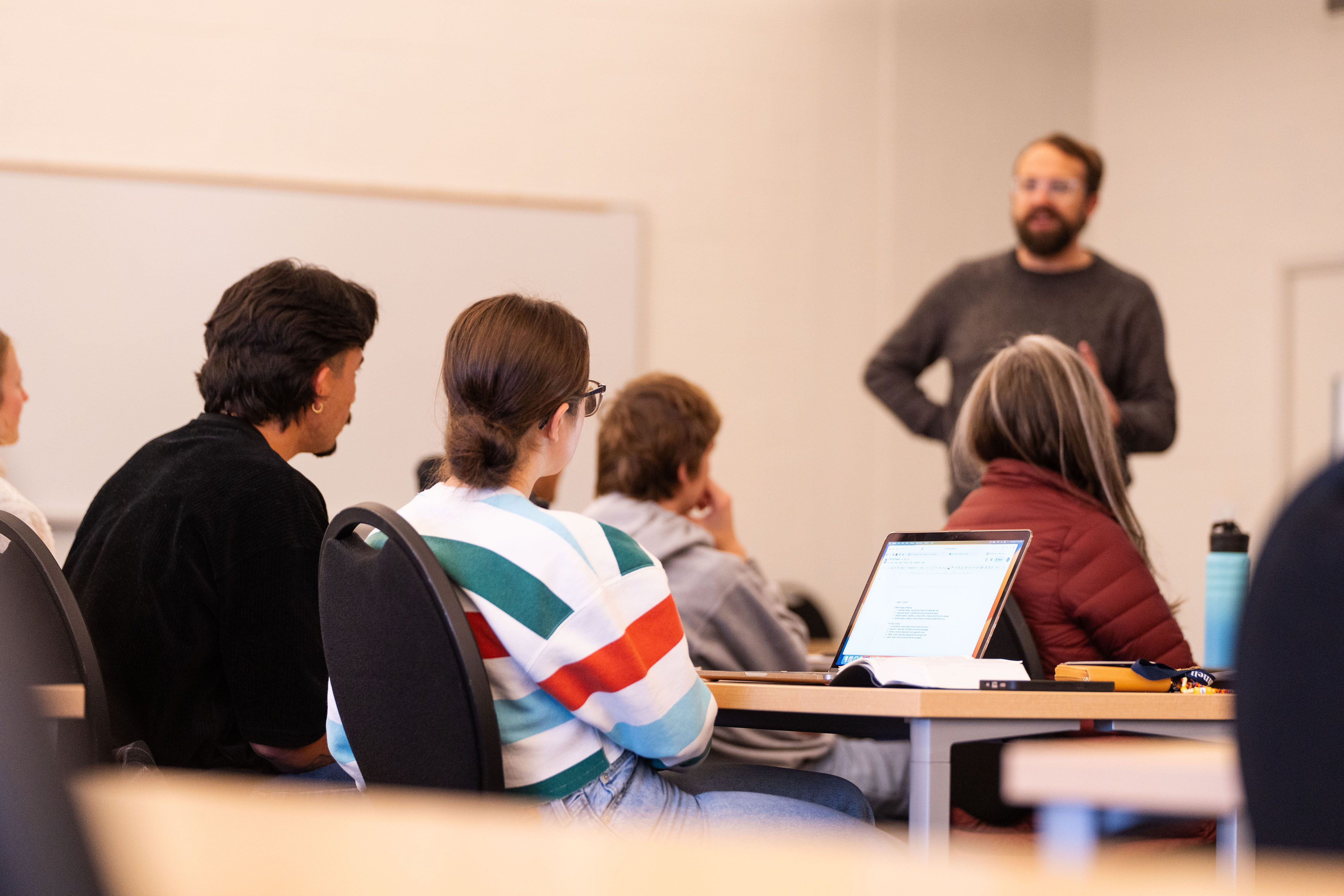 A classroom setting with students focussed on a teacher at the front of class.