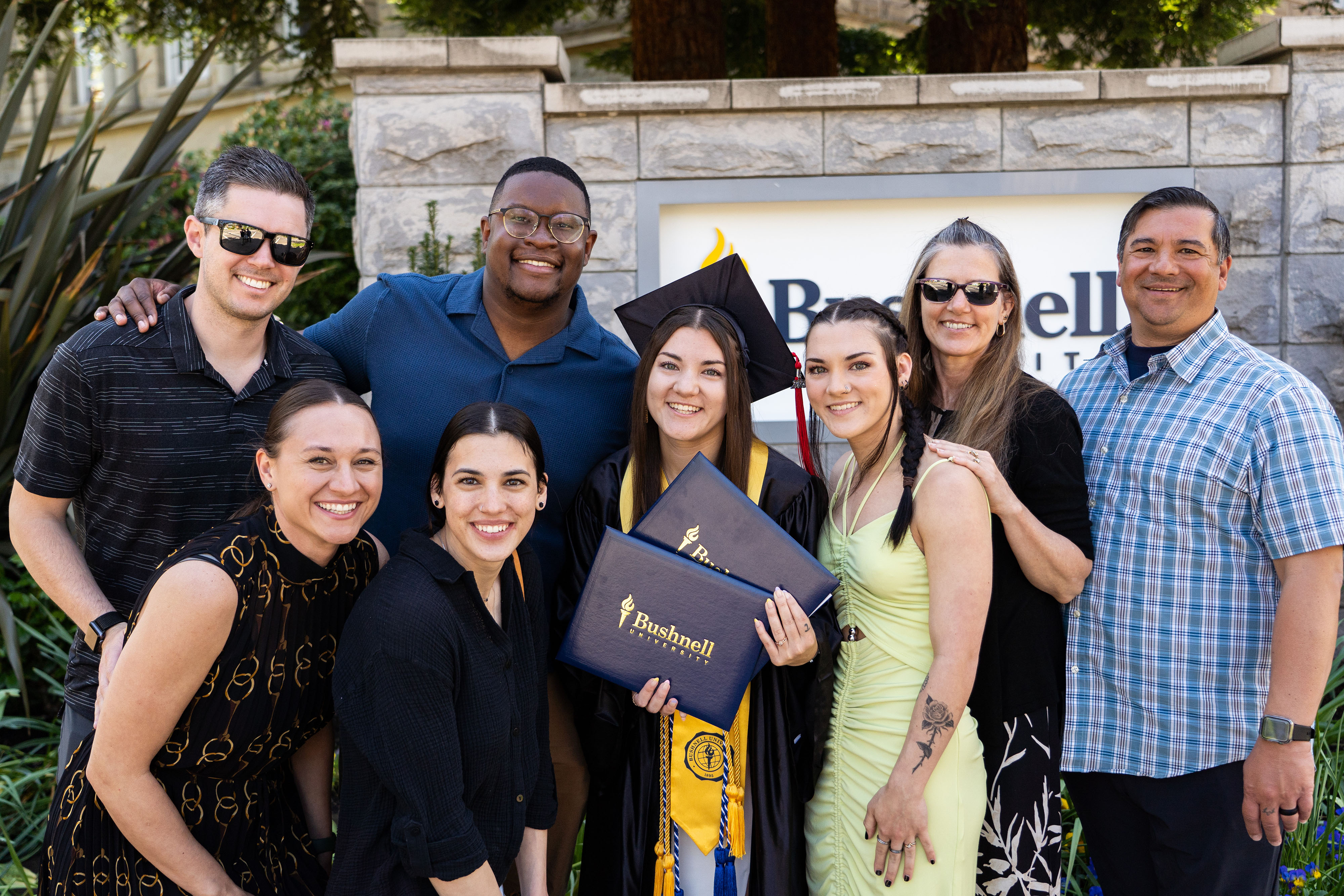 A big family photo with a Bushnell graduate student holding two diplomas.