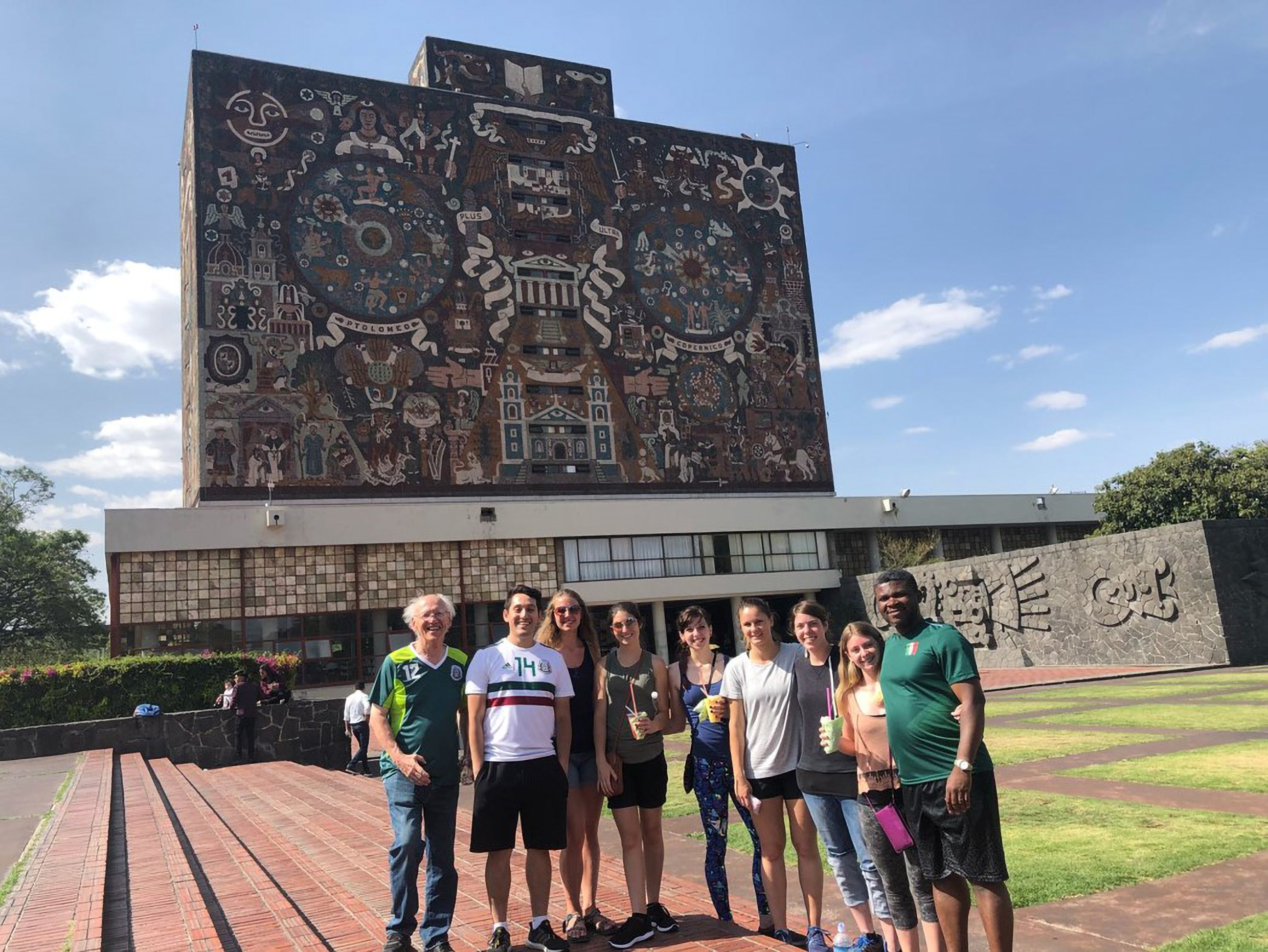 Students pose with faculty members in front of an artistic landmark in Mexico.