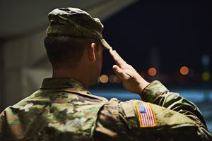 Military service member salutes while wearing a U.S. Army uniform.