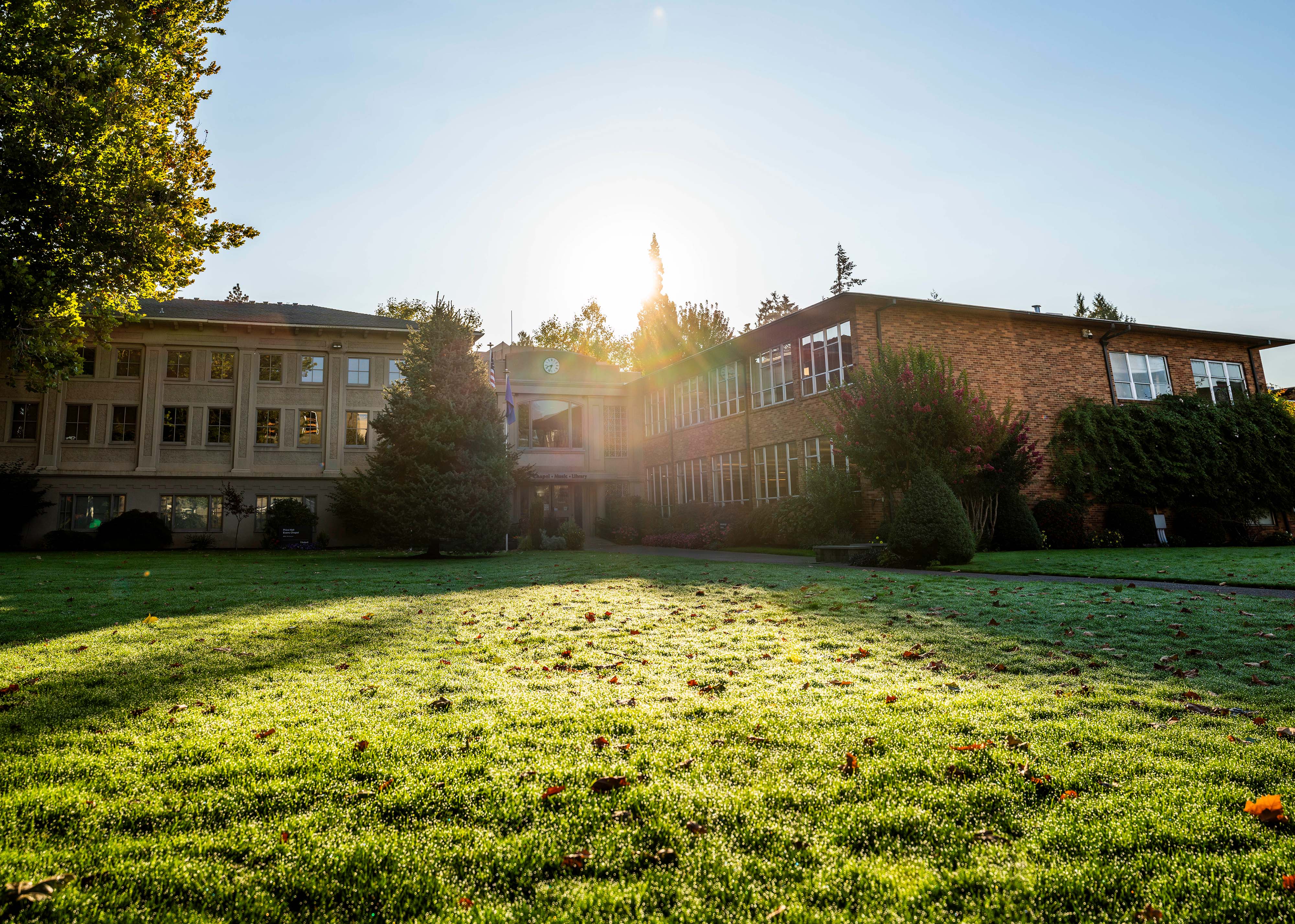 Bushnell Kellenberger Library photo taken in the morning with the sun shining on a sparkling dew lawn.