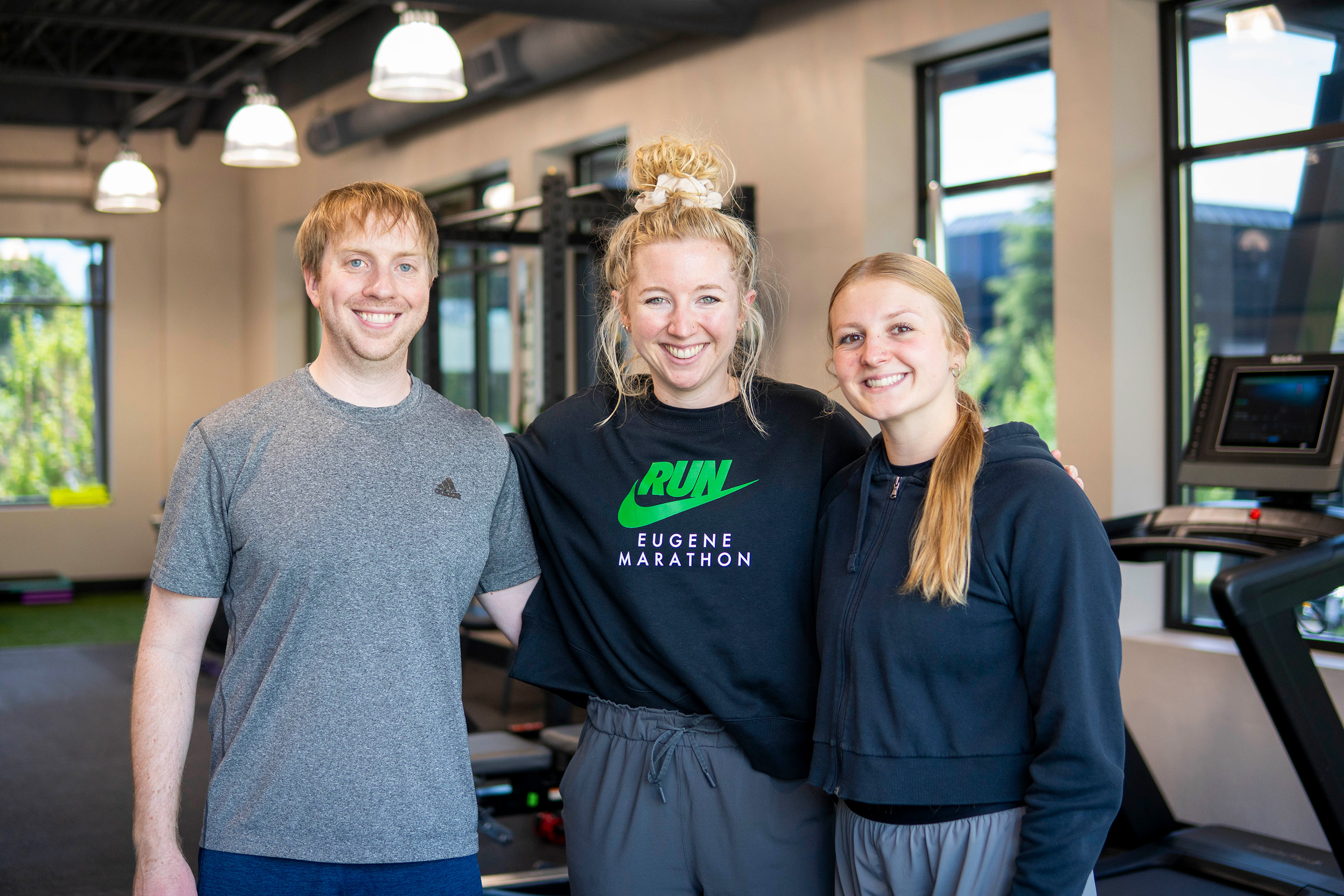 Physical therapy intern at local clinic posing with manager and team member in the weight room.