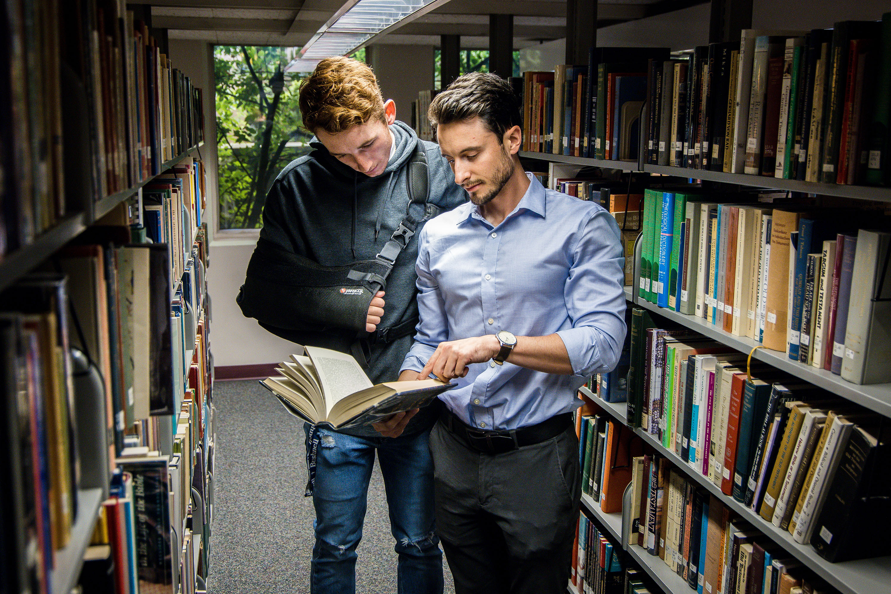 Teacher assists an injured student look for books in the university library.