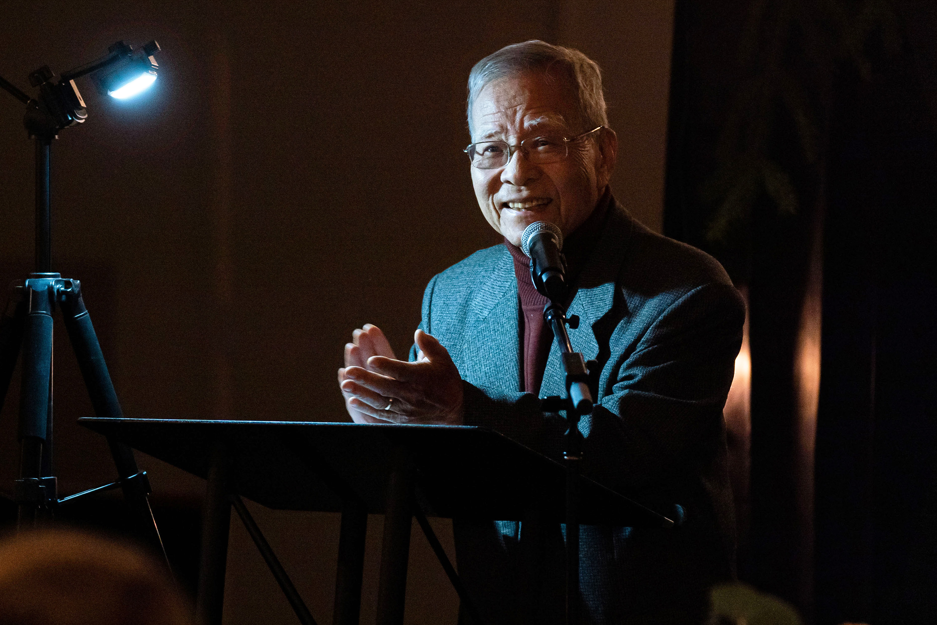 Dr. Song Nai Rhee smiles and claps while speaking during an honors program event.