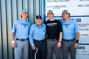 Three Bushnell baseball players pose with a program sponsor.