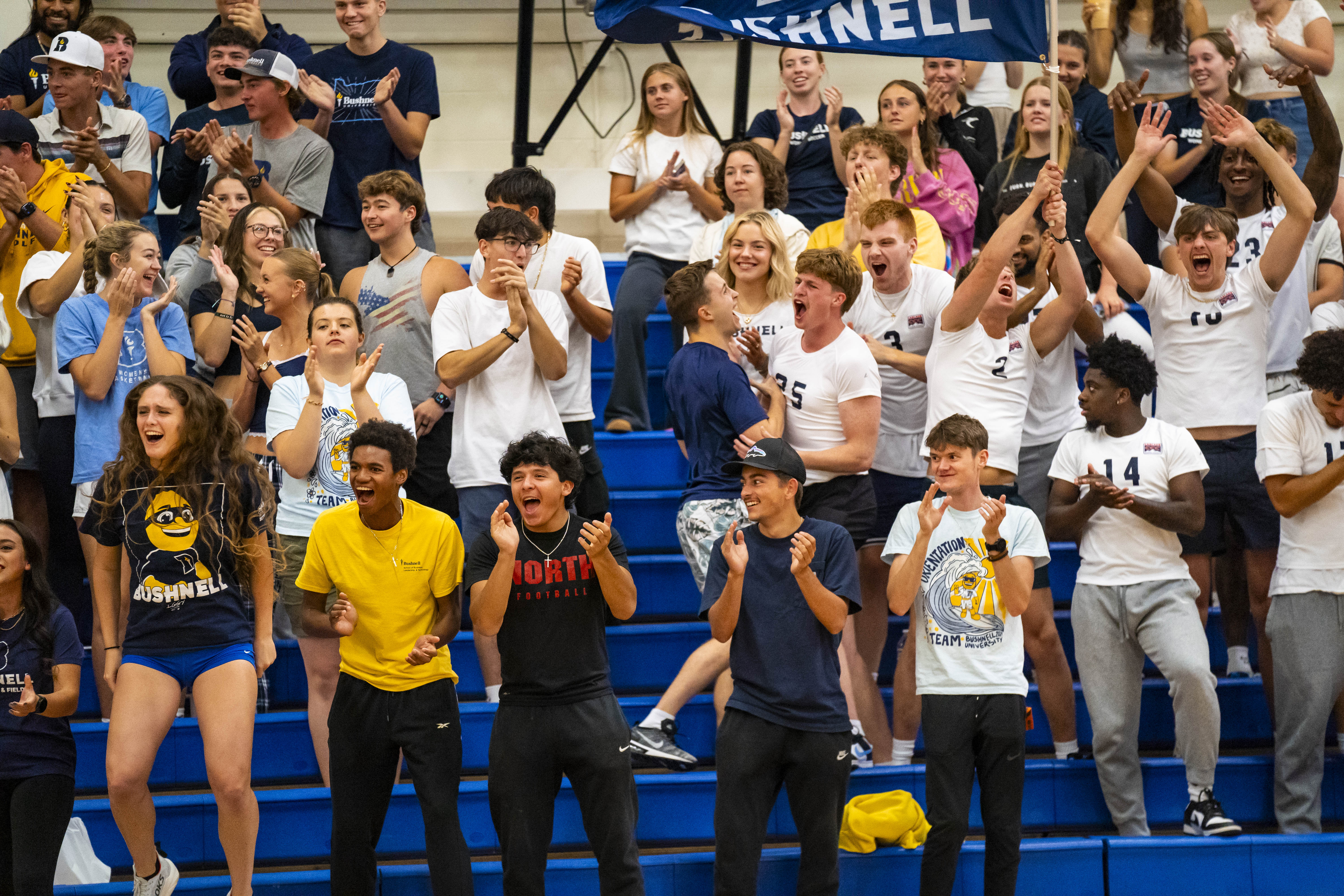 Large crowd of Bushnell University students cheering and having fun at a sports game.