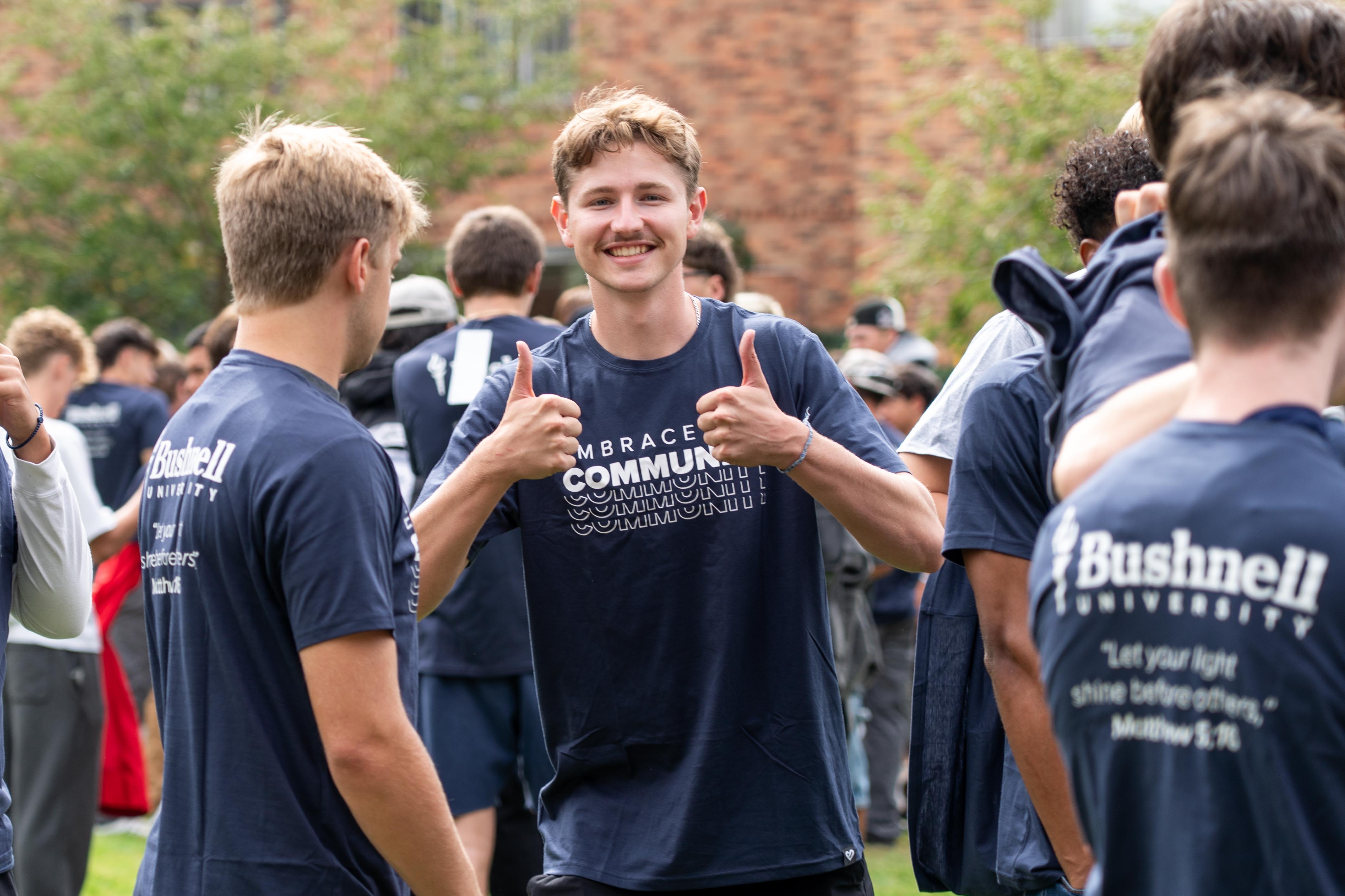 Bushnell University students gather outdoors during ETC Day wearing matching Embrace Community shirts.