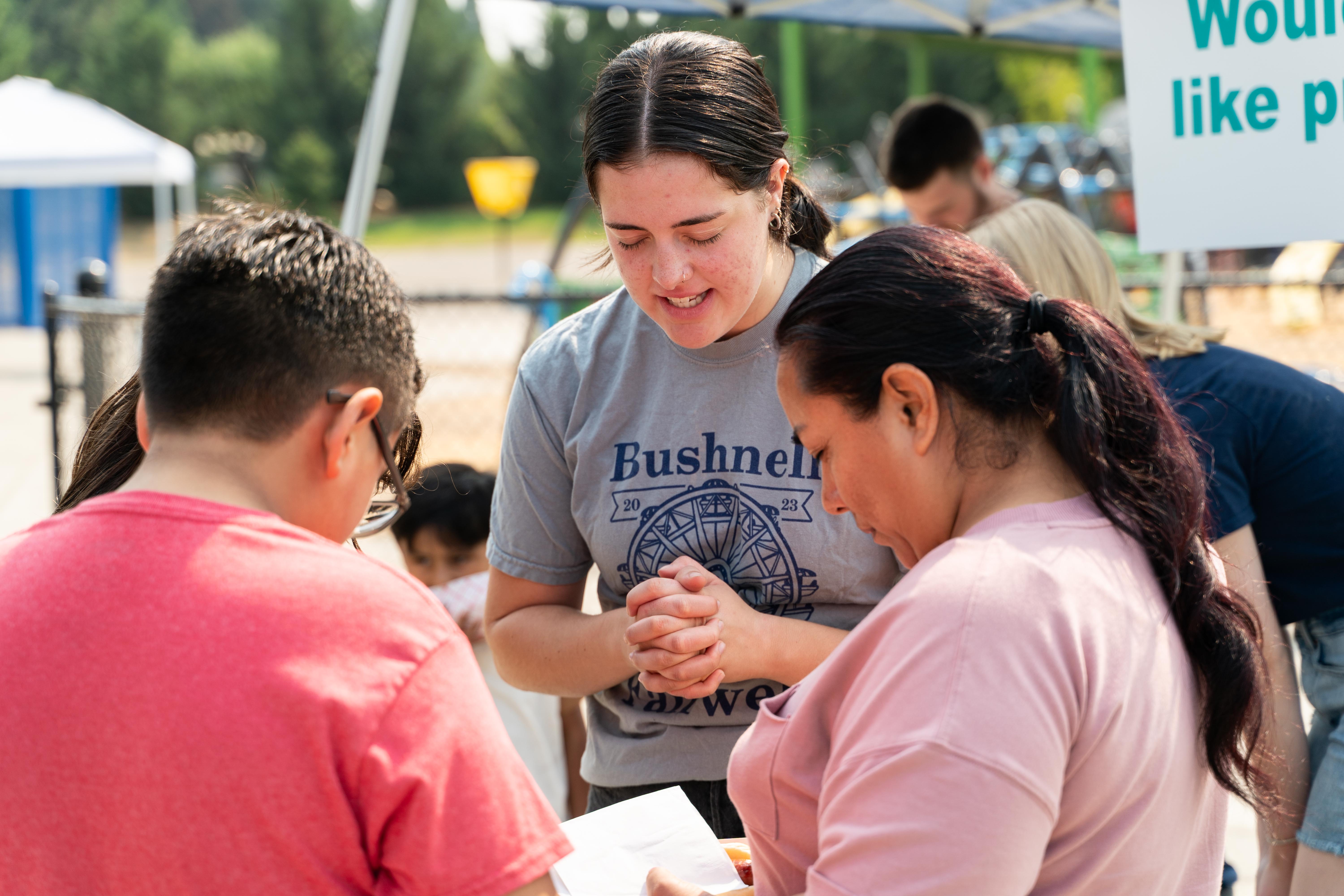 A Bushnell University student prays with community members during a local service and outreach event.