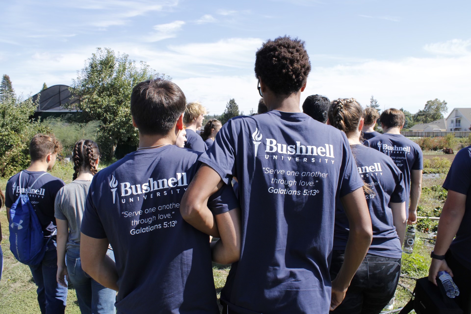 Bushnell University at work during a service day while showing a scripture verse on their shirt.