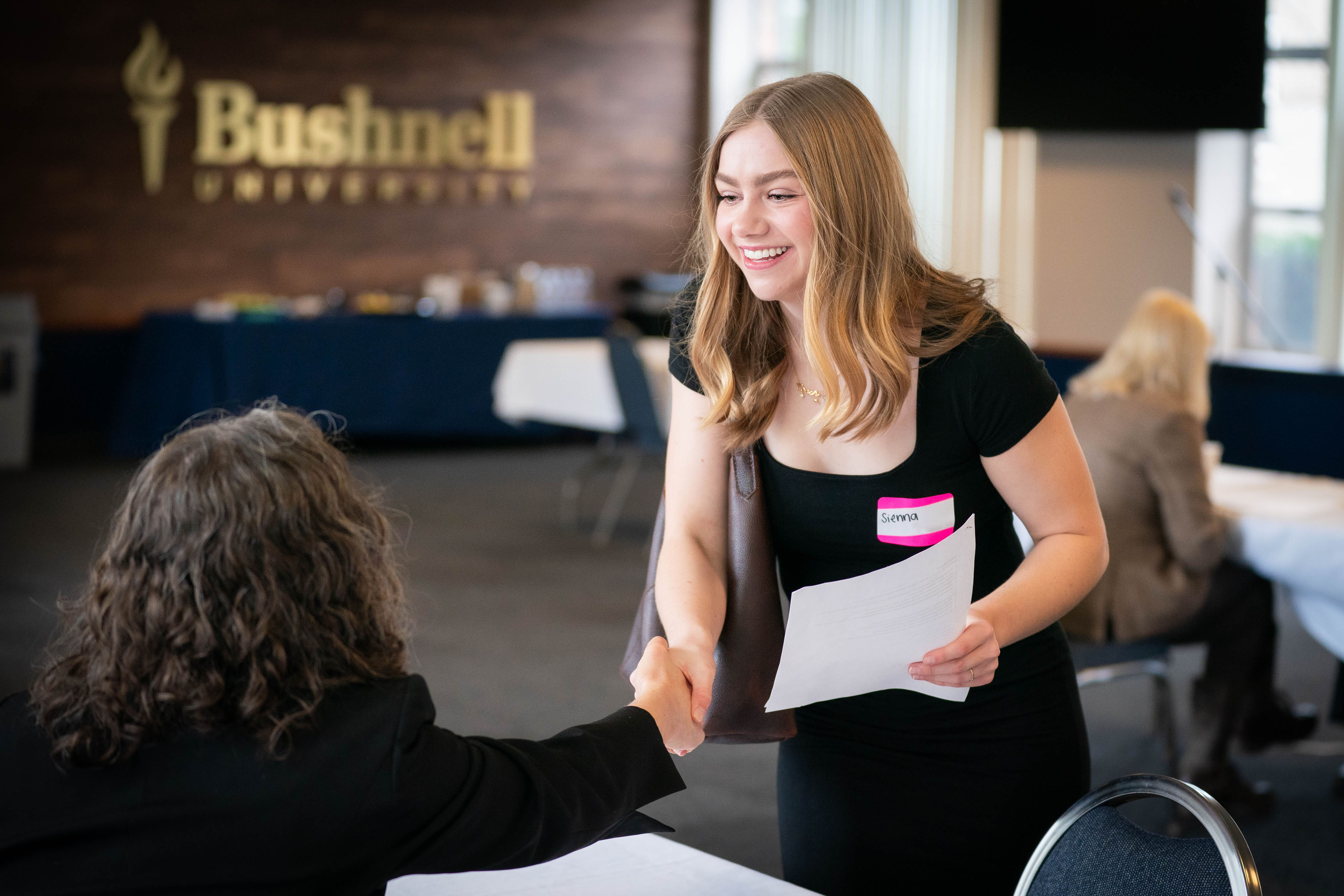 Professionally dressed student shakes hands with a business professional during a practice interview.