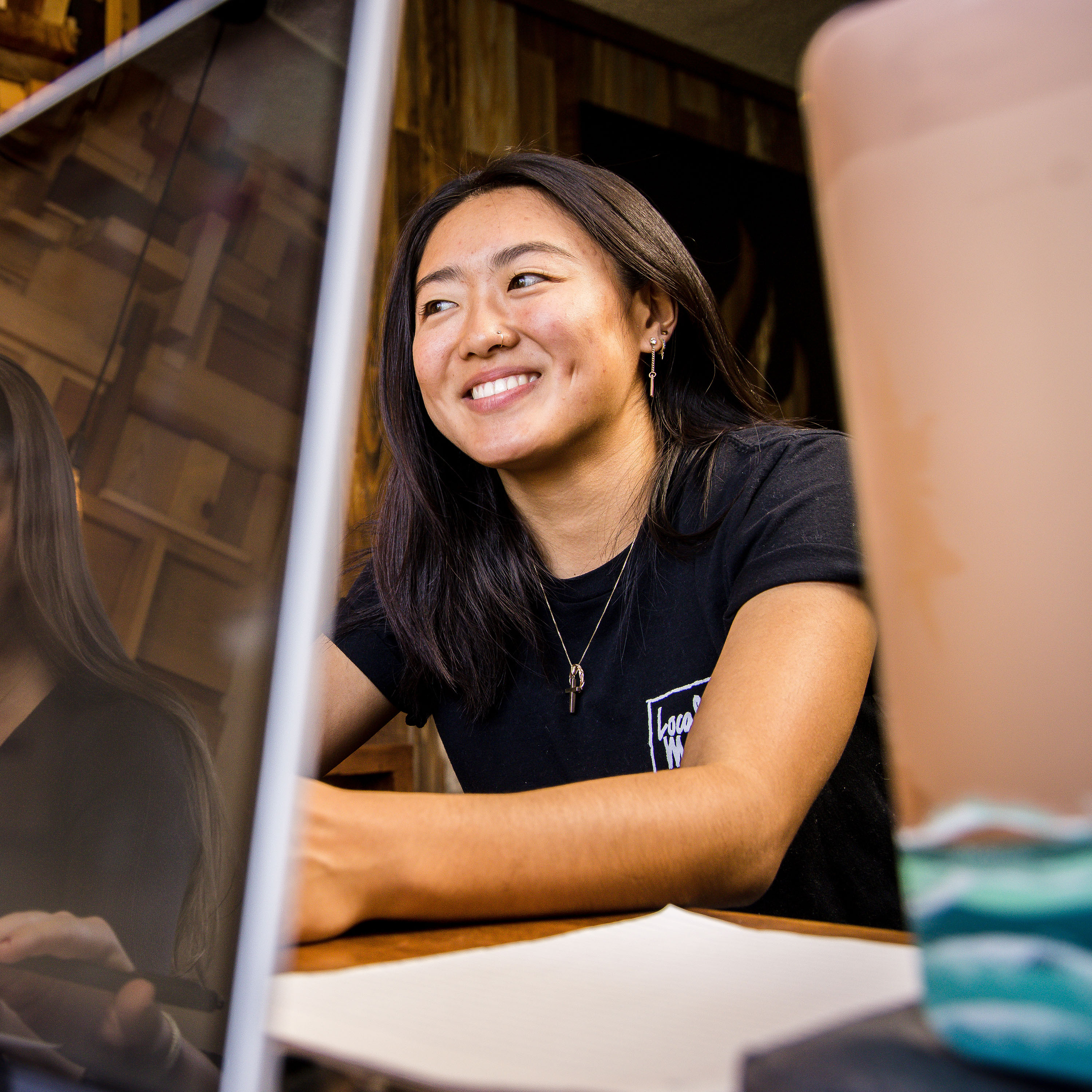 A student smiles with a computer screen.