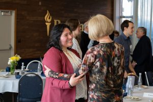 A smiling student and scholarship sponsor embrace at a lunch event.