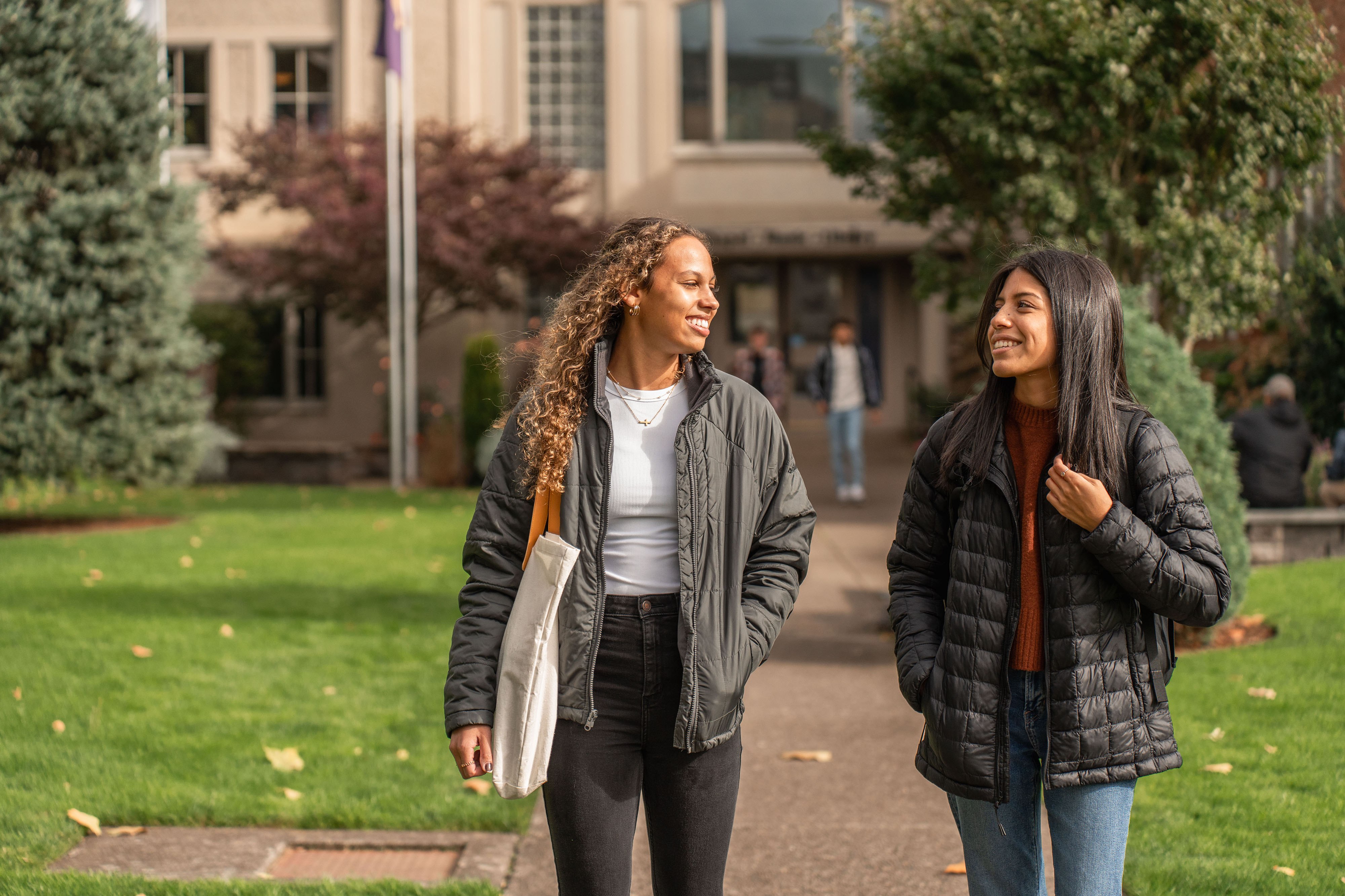 Two university students walk down a sidewalk while discussing mental health in the fall.