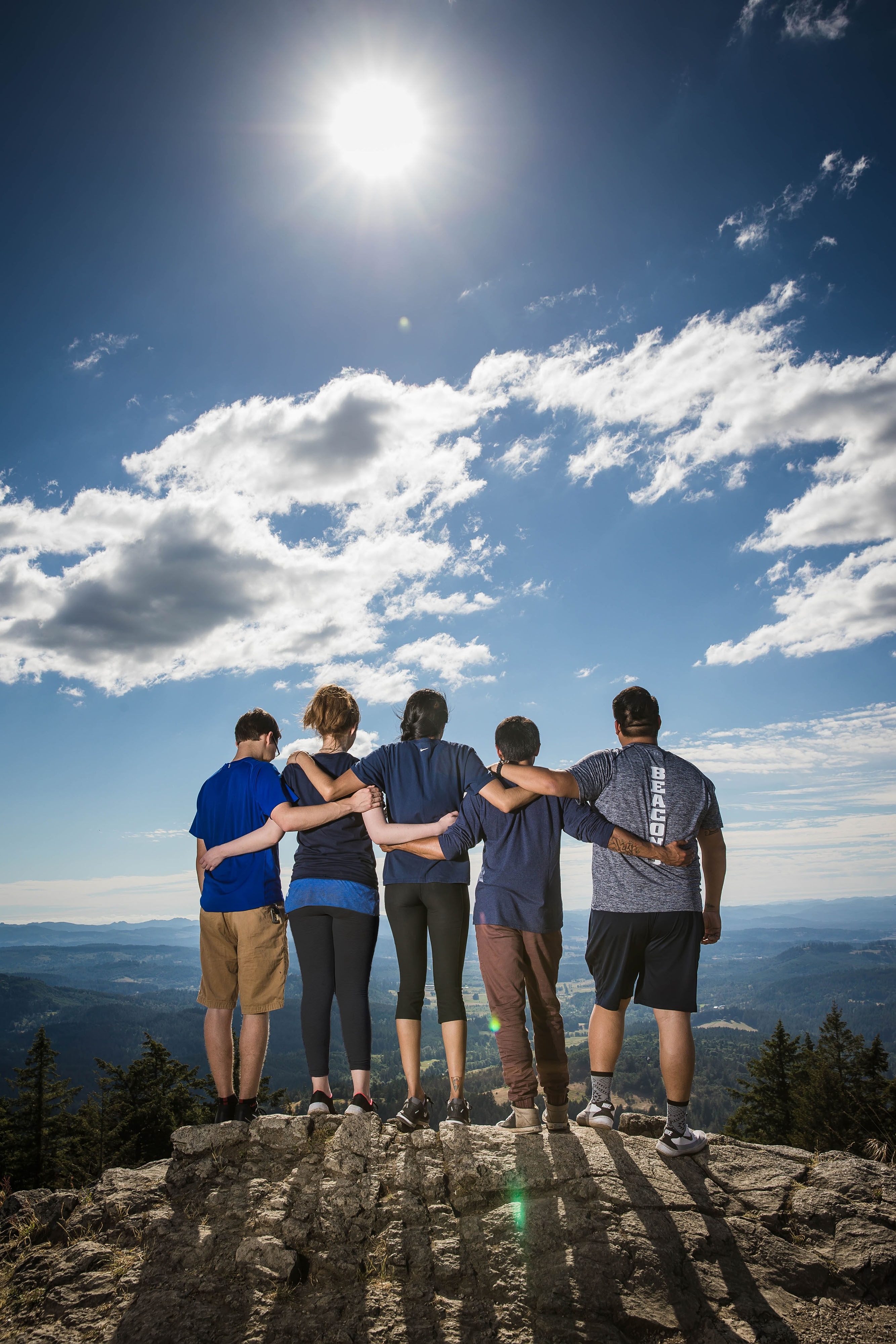 Five students overlooking Eugene with arms around each other as they stand on Spencer's Butte.