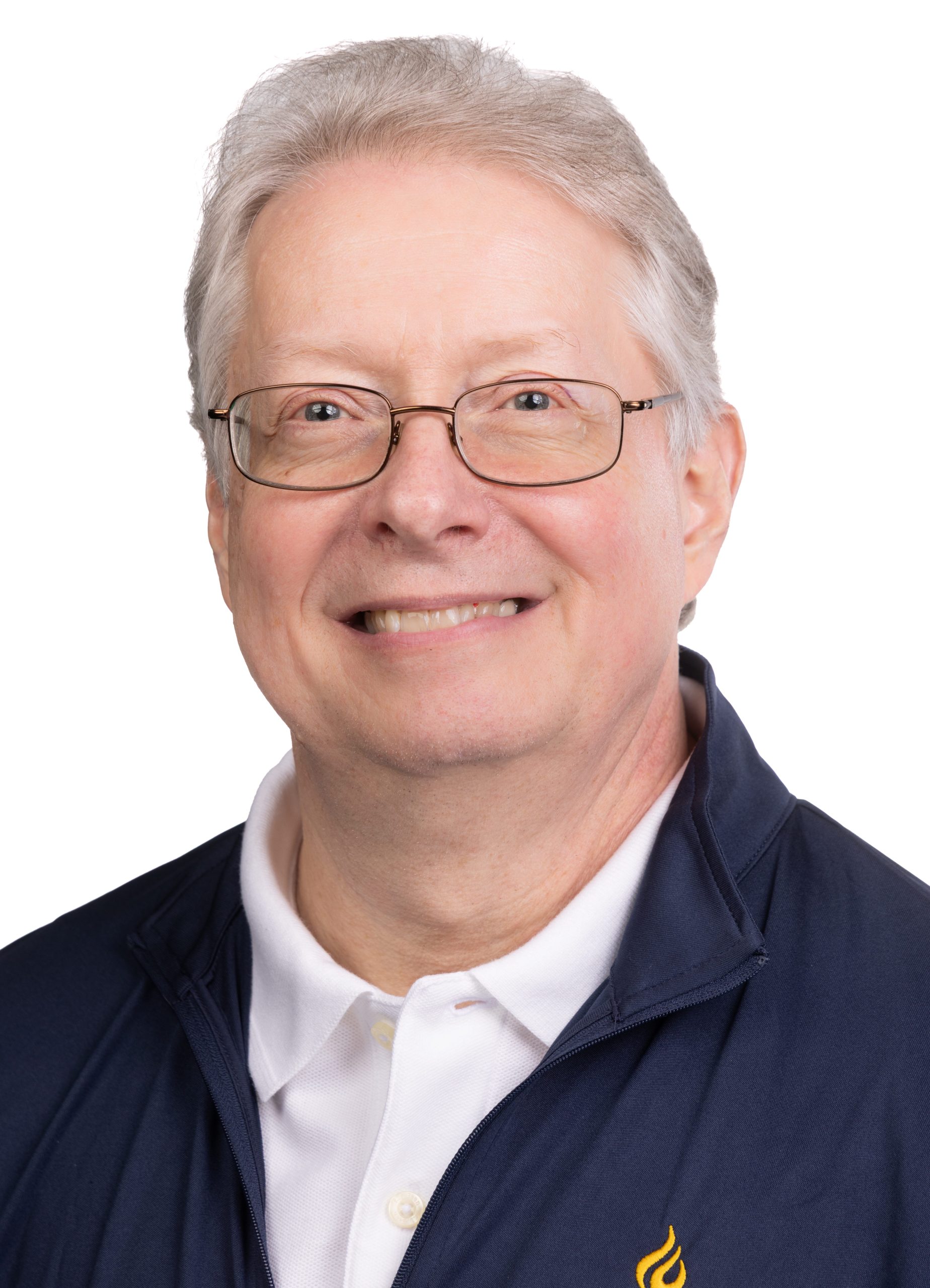 Portrait of a smiling older man with gray hair and glasses wearing a navy Bushnell jacket over a white polo shirt against a white background.