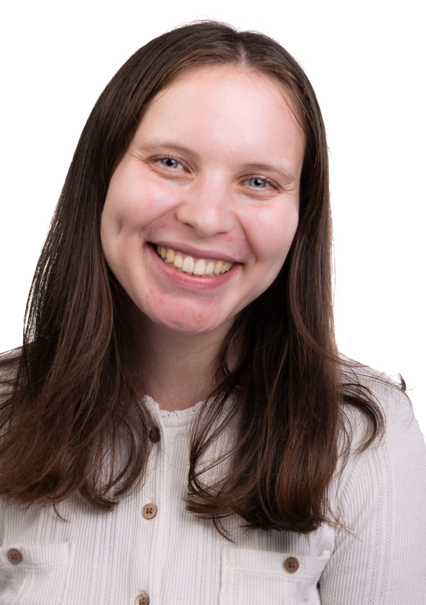 Portrait of a smiling young woman with long straight brown hair wearing a white blouse against a white background.