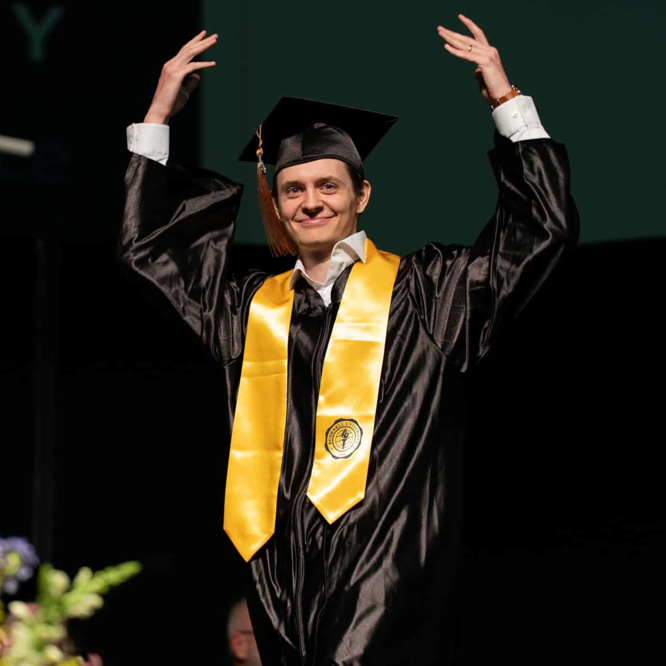 Bushnell University graduate celebrates on stage during commencement.