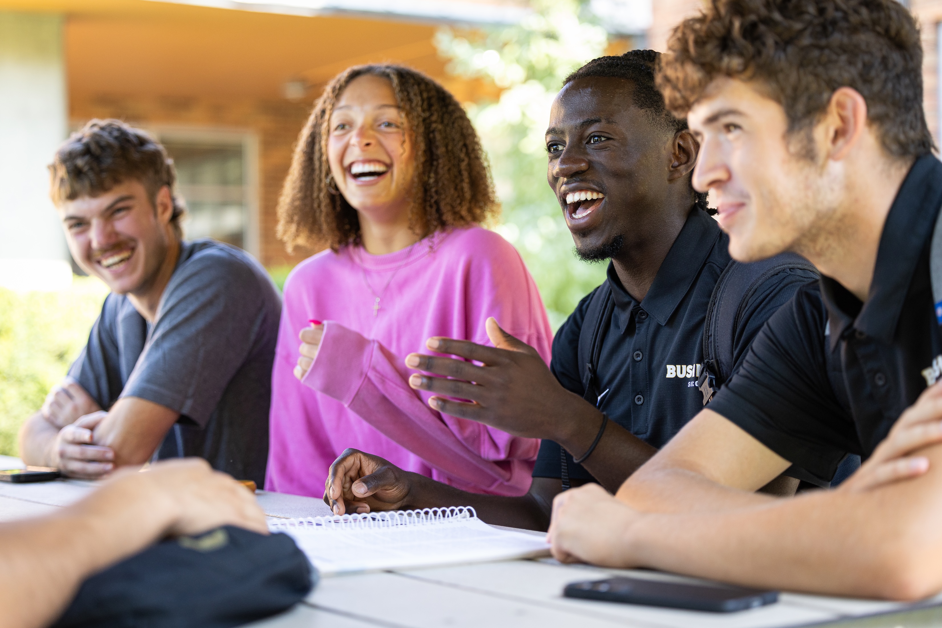 Bushnell University students laughing and talking together around an outdoor table.
