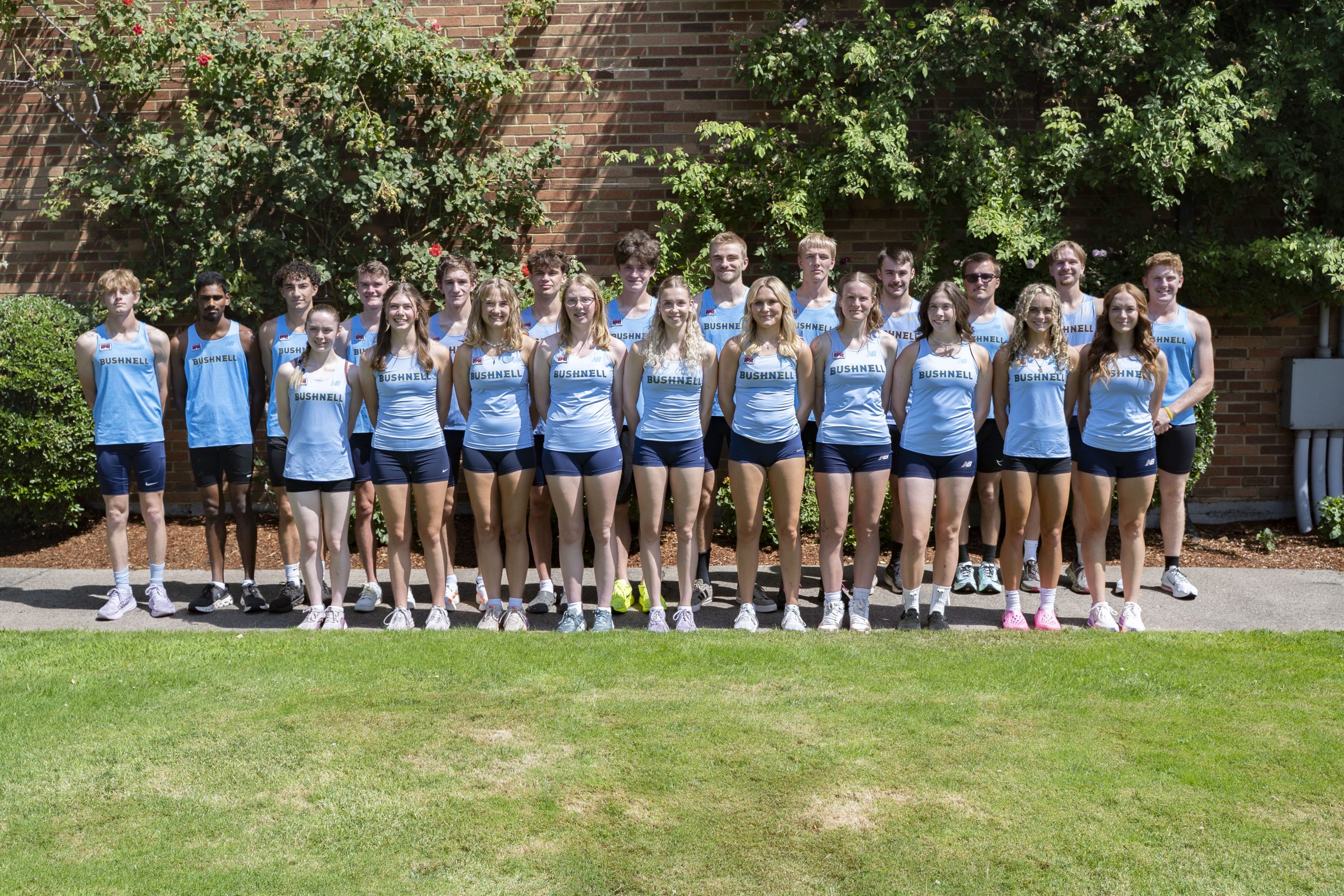 group of cross country students posing for a team photo outdoors.