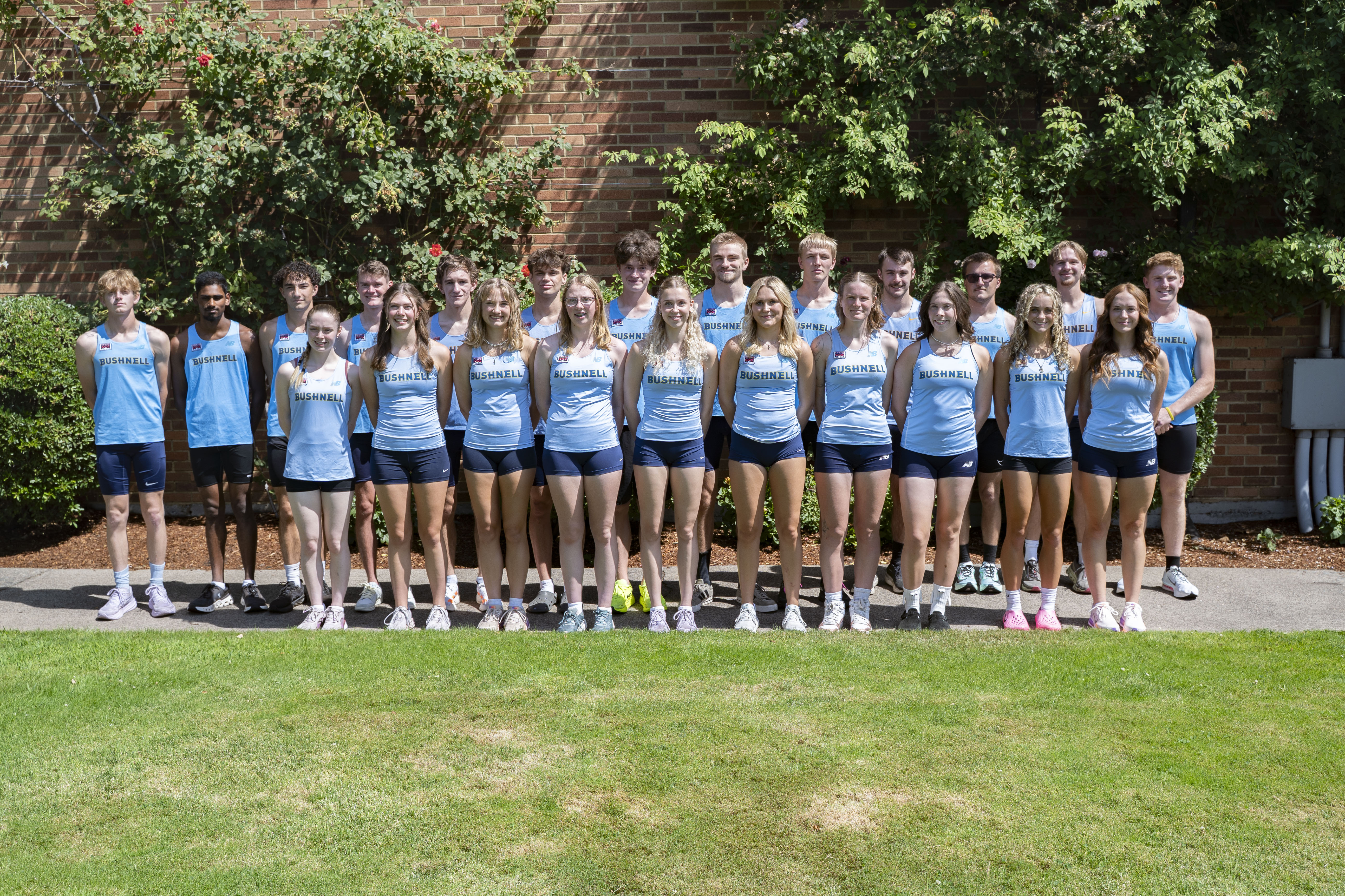 group of cross country students posing for a team photo outdoors.
