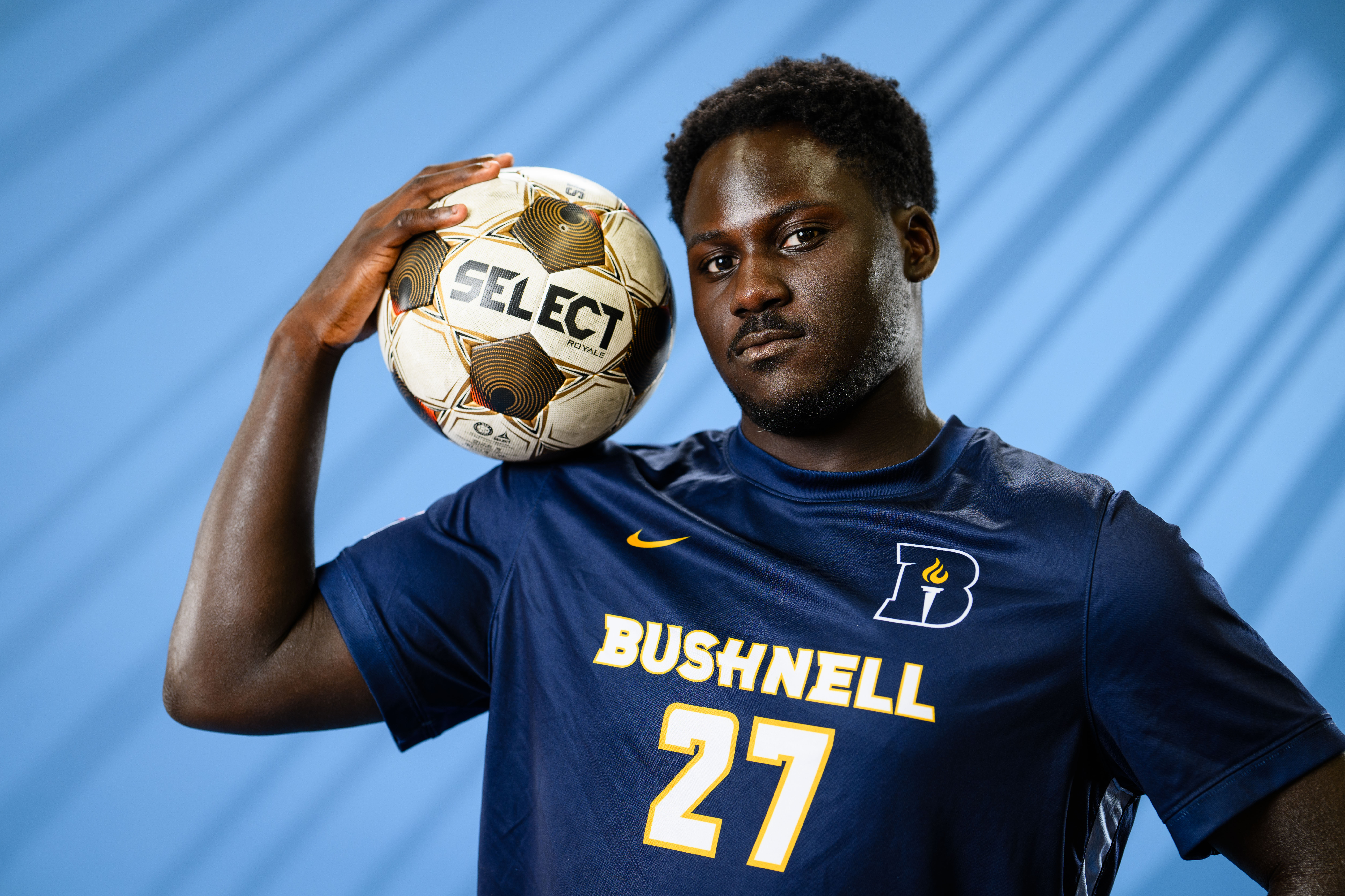 men's soccer player at media day holding a soccer ball.