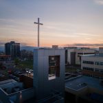 Bushnell University bell tower and cross overlooking campus at sunset.