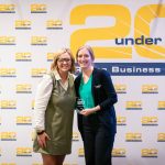 Carrie Gillies of Bushnell University smiles while holding her 2025 20 Under 40 Rising Business Stars award alongside another woman at the awards ceremony.