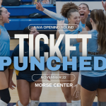 Bushnell University women's volleyball players celebrate on the court with a graphic announcing their NAIA Opening Round appearance on November 22 at the Morse Center.