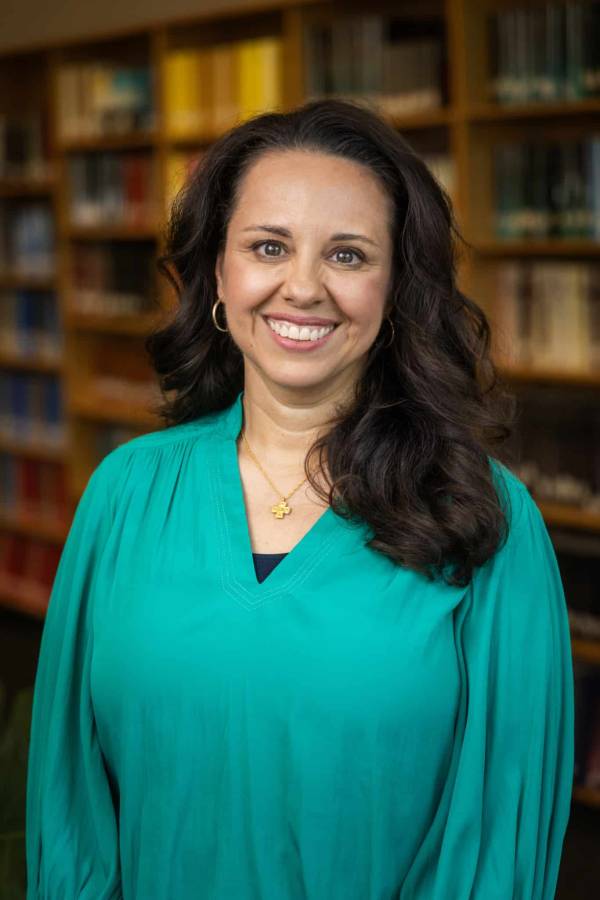 A female professor standing in front of a bookshelf in a library