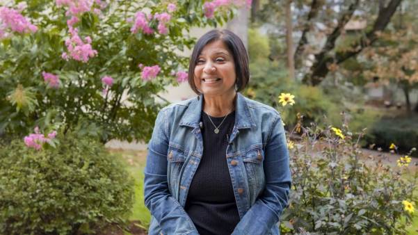 Female faculty member standing outside in front of bushes