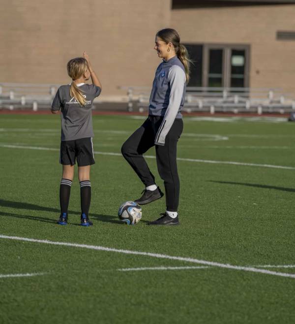 A female student athlete and a child playing soccer