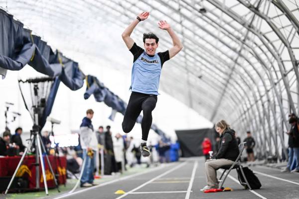 A track athlete in a blue shirt flexing