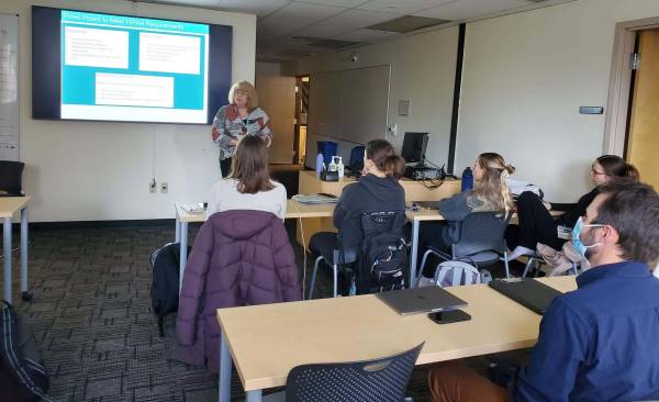 A person standing in front of a screen, presenting to ABSN students